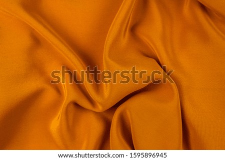 Golden silk or satin luxury fabric texture can use as abstract background. Top view.