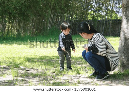A picture of wife and son talking in the park while watching the soil and grass.