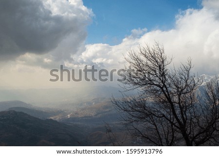 Mountain Peaks and Winter Sleeping Tree, Storming Clouds and Blue Sky.
