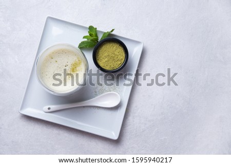 Japanese green matcha tea latte in clear glass on white background. Diet and vegan drink. Top view and copy space


