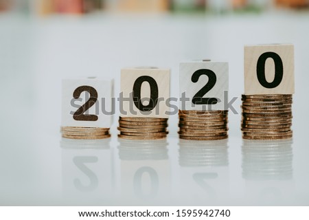 Wooden word number 2020 on stack of coins and  blurred city scape with copy space for text using as background business investment, new year, real estate, property concept.