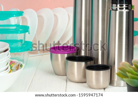 Thermos bottle against tableware in a kitchen