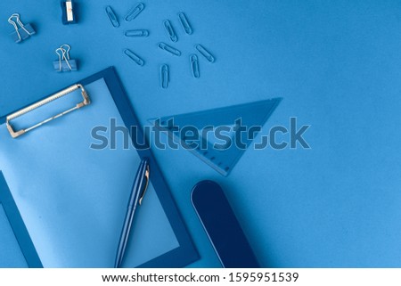 Classic blue colored top view photo of scattered stationery