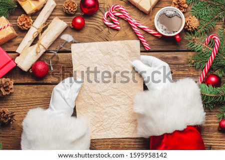 Santa Claus with empty paper sheet on wooden table
