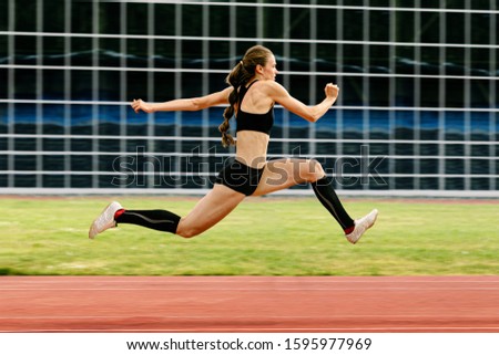 triple jump women jumper on stadium in background blurred glass facade building Royalty-Free Stock Photo #1595977969