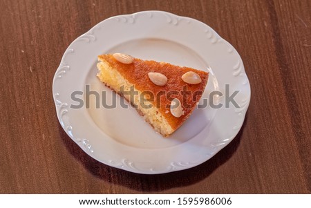 "ravani" traditional midle east sweet semolina Christmas cake with honey syrup and nus, served in white plate on wooden table
