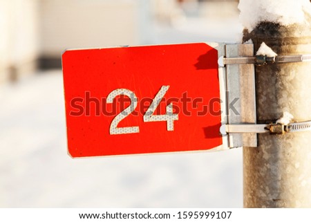 red sign with the number twenty four in white with winter background