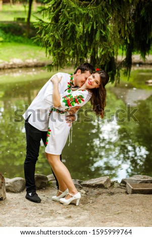 Amazing couple in national costumes hugging near the lake