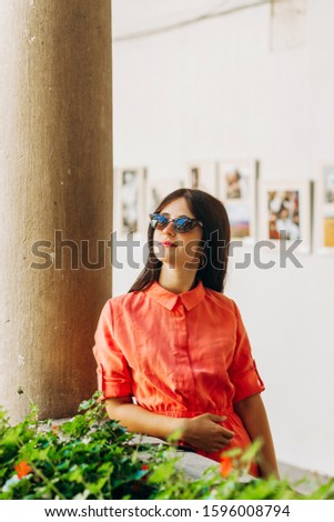 Stylish girl in glasses stands on the balcony