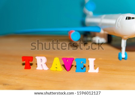 Tourism and travel concept, toy airplane and color letters on wooden background.