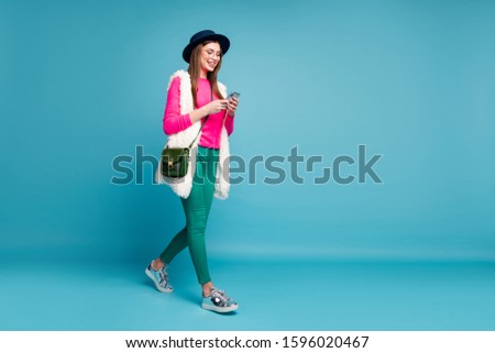 Full length body size view of her she nice attractive lovely cheerful cheery girl walking spending free time using gadget isolated on bright vivid shine vibrant green blue turquoise color background