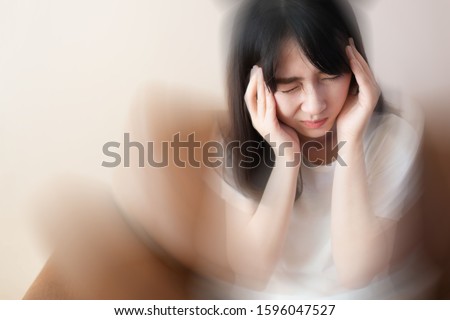 Young female suffering from dizziness, vertigo, headache while sitting on couch at home. Cause of dizzy inclued migraine, stress, stroke, BPPV, Meniere’s disease or brain tumor. Health care problem. Royalty-Free Stock Photo #1596047527