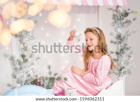 Cute blonde girl with christmas star decoration near christmas tree. happy new year concept. make a wish