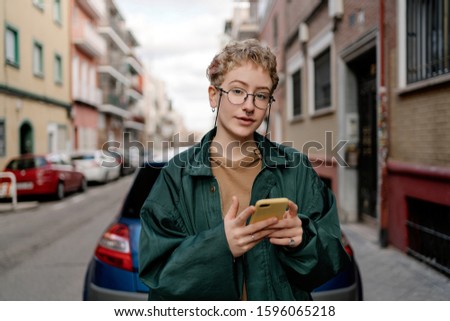 Stock photo of a pretty woman in the street texting with her smartphone