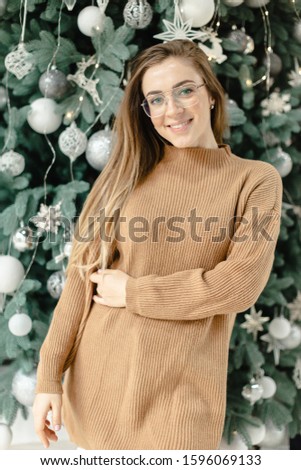 Beautiful young woman near Christmas tree with Christmas decorations with oat cake and milk. Christmas concept. New Year concept. winter holidays