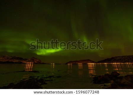 Polar lights, Northern lights over city in the North of Europe , cloudy sky, Lofoten islands, Norway, long exposure.