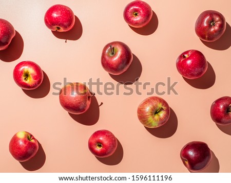 Delicious red apples on orange or coral pink background pattern. Colorful fruit frame. Flat lay or top view, Hard light. Creative concept.