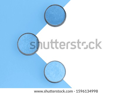Eyeshadows in different shades of blue on trendy blue and isolated white background. Color of the year 2020 concept. Flat lay. Copy space.