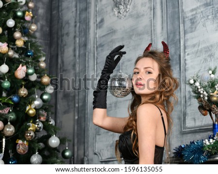beautiful girl dressed as a demon with a mirror fortune-telling ball in her hands