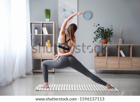 Beautiful young woman practicing yoga at home Royalty-Free Stock Photo #1596137113