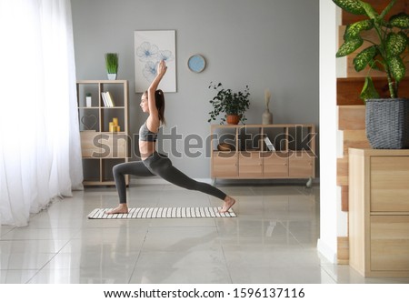 Beautiful young woman practicing yoga at home Royalty-Free Stock Photo #1596137116