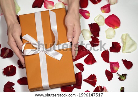 Orange gift box on background of rose petals. Valentine day, mother day, wedding, 8 march of concept. Gift stock images