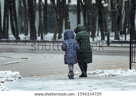 people walk down the street in a snowstorm during rush hour winter day, a storm warning and a cold snap Royalty-Free Stock Photo #1596154729