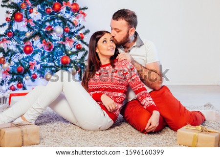husband and wife on Christmas trees offer gifts for the new year