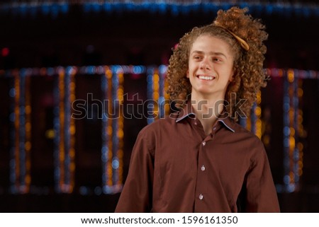 Celebration, people and holidays concept - happy curly guy having a Christmas or New Year party on the background of festive lights
