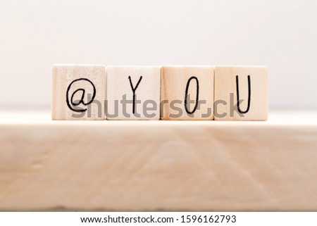 Wooden cube signs with At sign and the word you on white background, tag someone on social media concept closeup