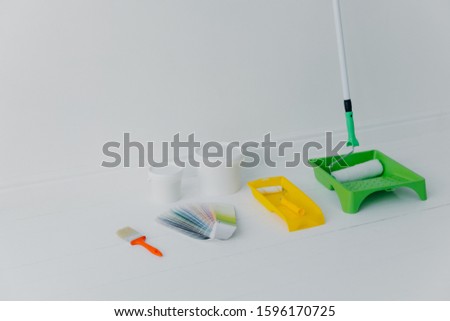 Set of painting. Paint roller in tray, paintbrush and color sample isolated over white background. Necessary tools and paint for painting walls of room. Home remodeling and renovation concept