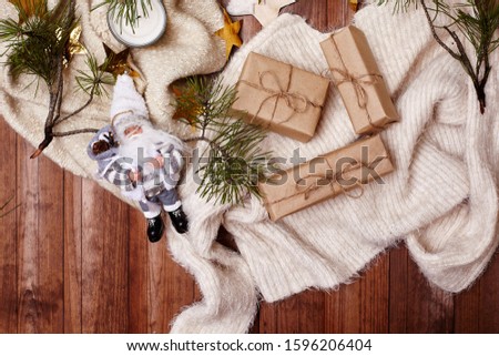 Cozy Winter Composition. Hygge Style. Christmas Gifts, Rustic Decorations, Gold Stars Tinsel and Warm Knitted Sweater on Wood Background. Flat Lay, Top View