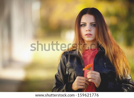 Beautiful girl holding a flower in the autumn forest