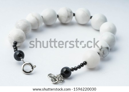 Handmade bracelet made of cacholong, black spinel and agate on a white background