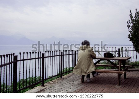 old man sits on a bench against seascape