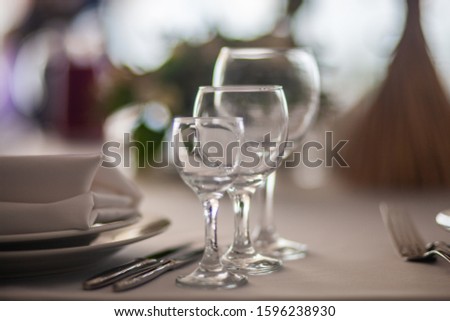 Screensaver for your desktop. Outdoors in. On open air. Cutlery on the table. Wine glasses are large and small. Table setting. White tablecloth. Plates. Knife. Fork.