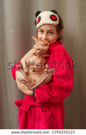 Picture of adorable young Caucasian female hugging her cute highbred pet. Sphynx cat with no fur purring in arms of her happy teenage female owner. Pets and people. girl with a sphynx cat in her arms