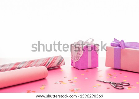 valentines confetti, scissors, wrapping paper, gift boxes on pink surface isolated on white
