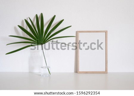 Modern home decoration with frame photo and palm leaf in vase on table