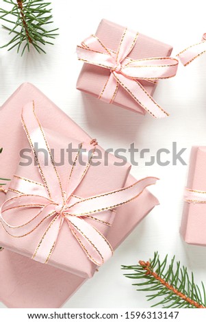 Christmas flat lay. Holiday gifts in boxes in pink packaging and fir branches on a white background with copy space, top view.