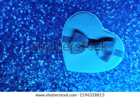 Gift heart box on blue sparkling glitter paper background. Valentine's day concept.