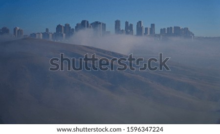 tall buildings behind fog in daytime