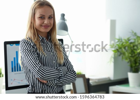 Portrait of presentable young woman posing with crossed arms in private office. Happy smiling ceo manager in striped blouse. Copy space in right side. Marketing concept