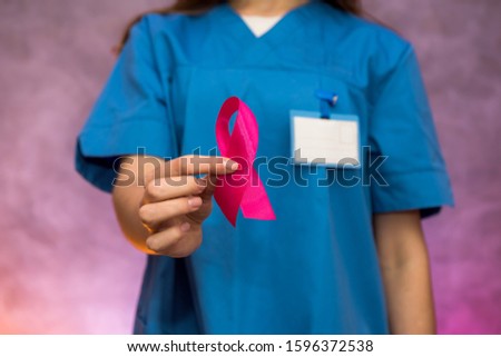 Attractive woman doctor holding red ribbon. Aids company