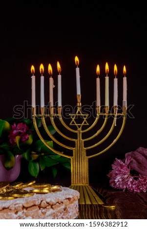 Festive menorah with white burning candles and cake with chocolate coins on the top. Jewish holiday concept.