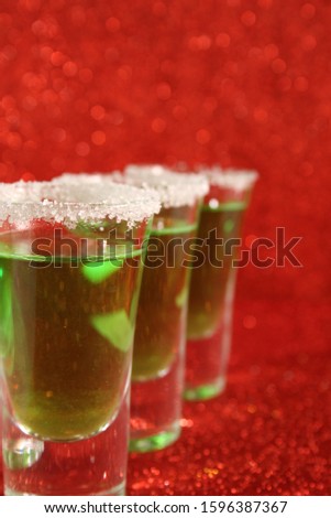 Two glasses with a green drink. Background from red spangles.