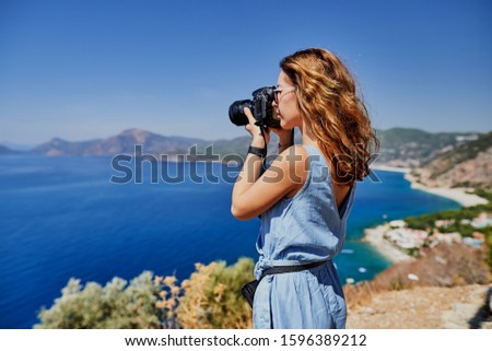 Beautiful woman professional photographer with dslr camera shooting landscape in sunset light in Turkey