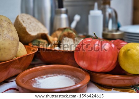 Still life of organic and fresh natural vegetables. Potatoes, tomatoes, lemon, bread, harina, mushrooms, vegetables and some kitchen pots in the background out of focus