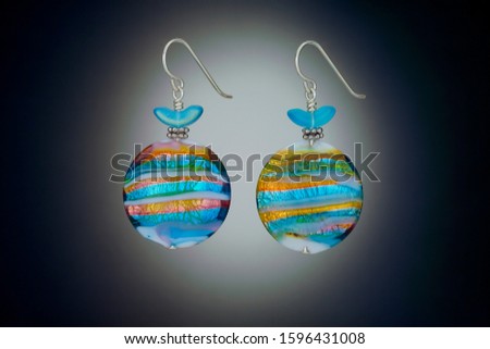 Colorful handcrafted art glass lollipop beads and french wires make up these earrings. Shown against a Vignetted background.