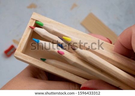 wooden pencil case with colour pencils on a creativ grey background for back to school